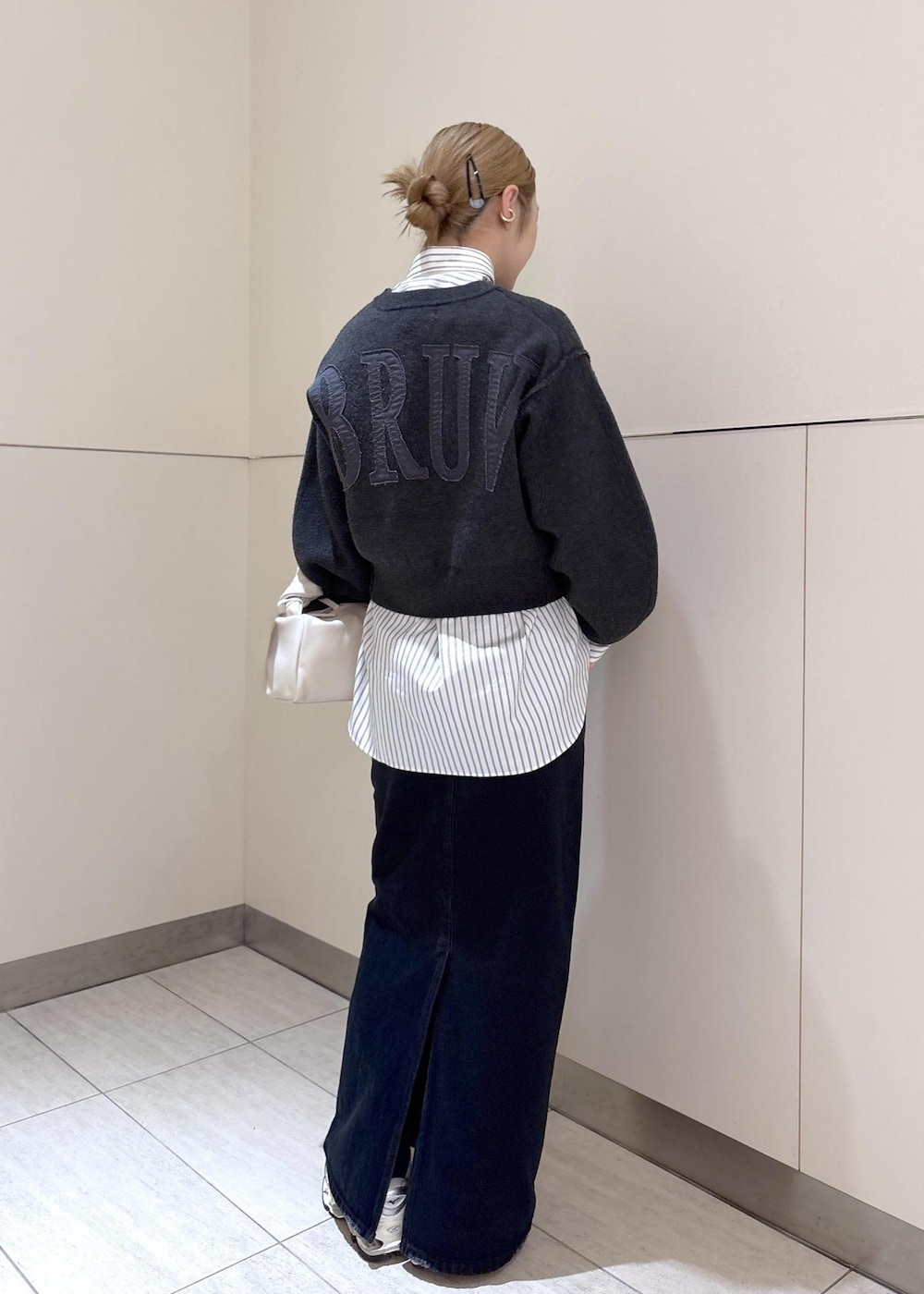 ホワイト系のスニーカー、グレー系のニット/セーター、ホワイト系のハンドバッグを着用したレディースの冬コーディネートの2枚目の写真