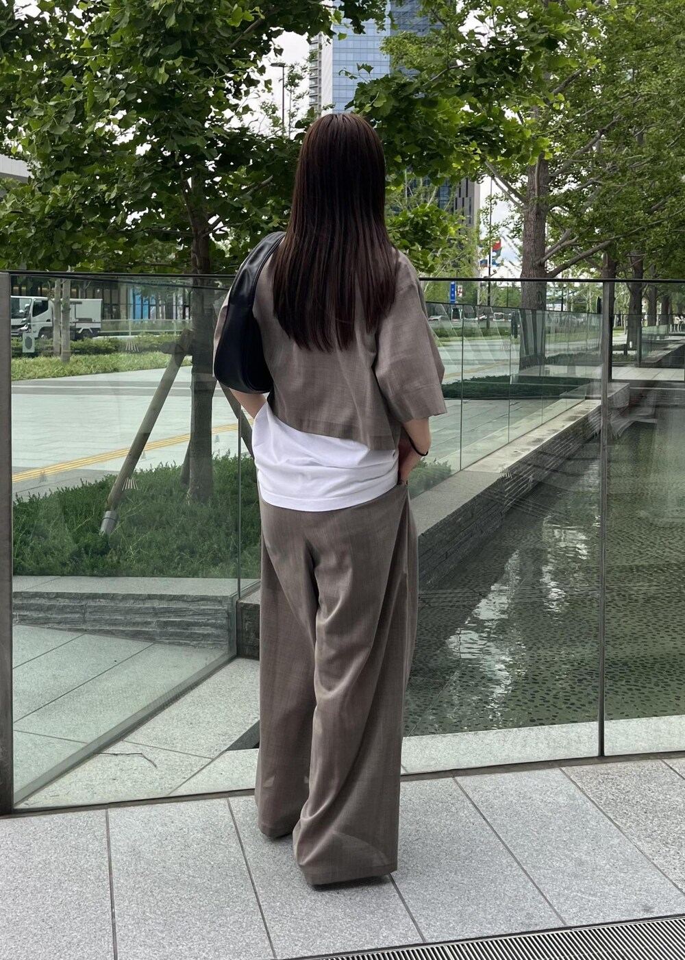 ベージュ系のサンダル、ブラック系のハンドバッグ、ベージュ系のスラックスを着用したレディースの夏コーディネートの2枚目の写真