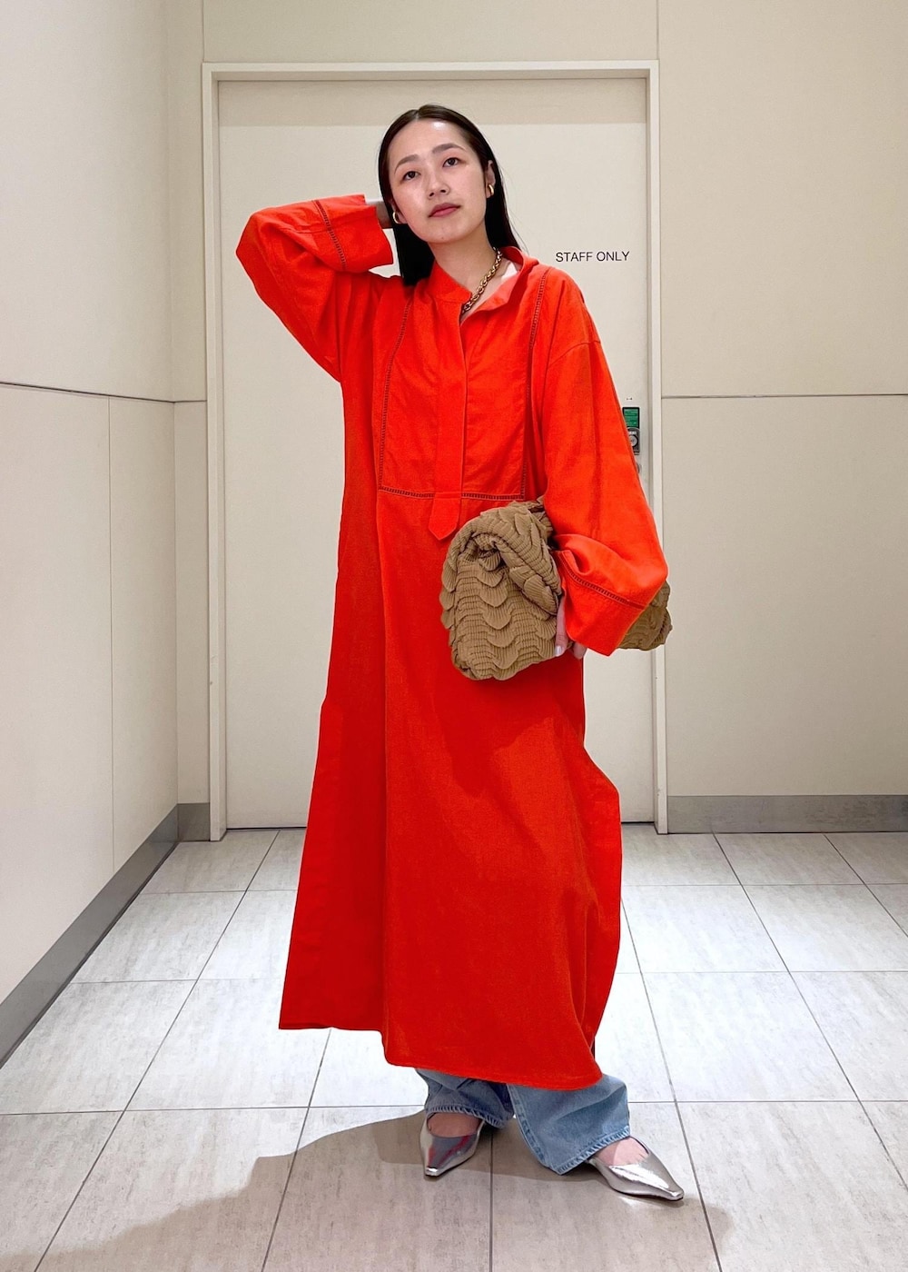 ブルー系のデニムパンツ、レッド系のワンピース、シルバー系のサンダルを着用したレディースの春コーディネートの2枚目の写真