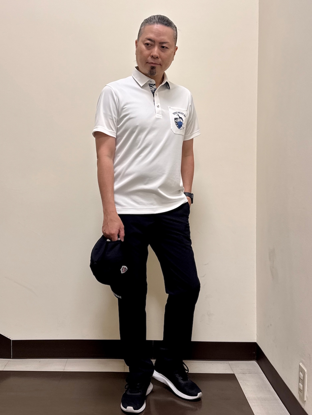 ホワイト系のポロシャツ、ブラック系のその他パンツ、ブラック系のキャップを着用したメンズの夏コーディネートの6枚目の写真