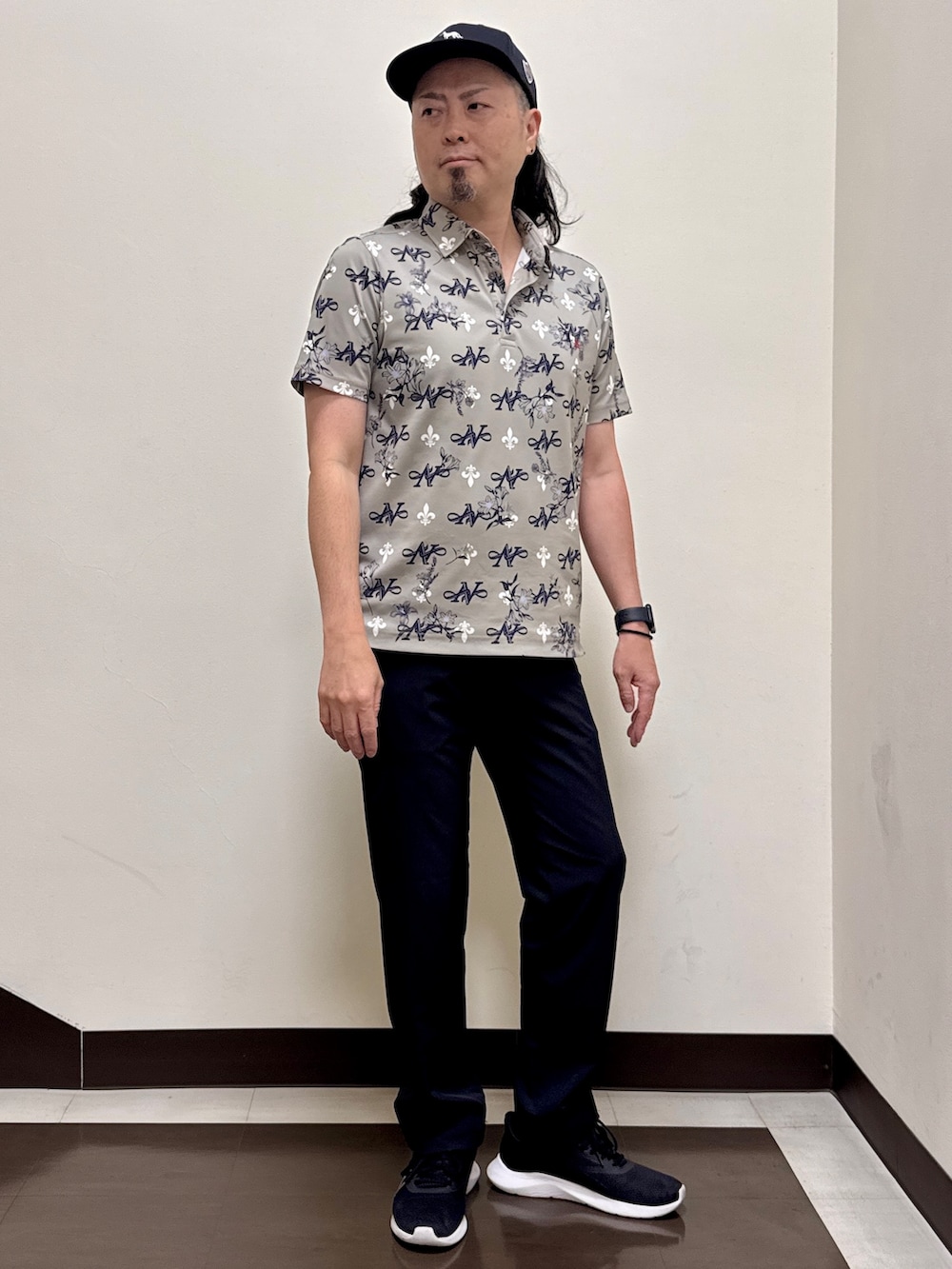 ベージュ系のポロシャツ、ブラック系のその他パンツ、ブラック系のキャップを着用したメンズの夏コーディネートの5枚目の写真
