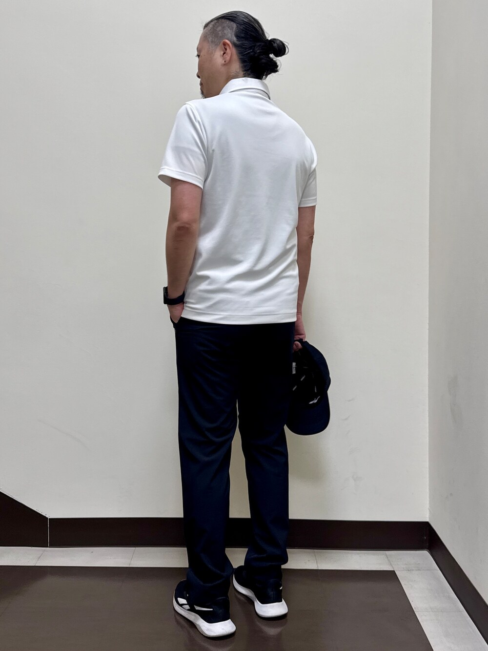 ホワイト系のポロシャツ、ブラック系のその他パンツ、ブラック系のキャップを着用したメンズの夏コーディネートの3枚目の写真