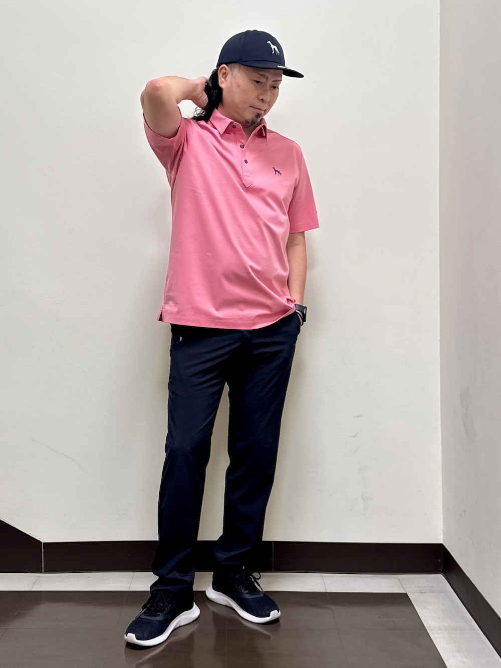 ピンク系のポロシャツ、ブラック系のその他パンツ、ブラック系のキャップを着用したメンズの夏コーディネートの5枚目の写真