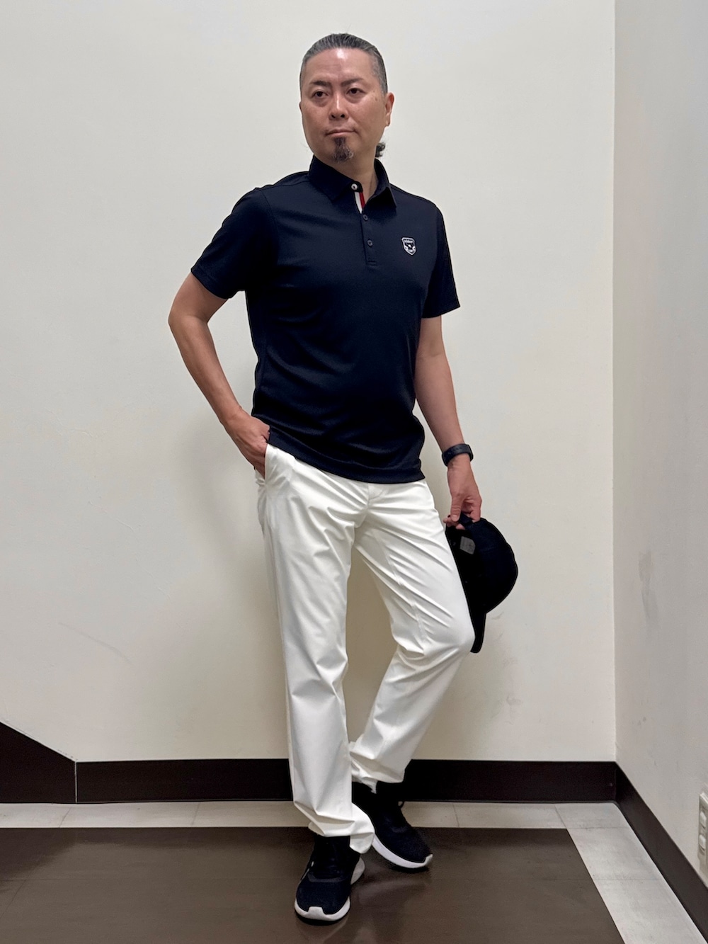 ブラック系のポロシャツ、ホワイト系のその他パンツ、ブラック系のキャップを着用したメンズの夏コーディネートの4枚目の写真