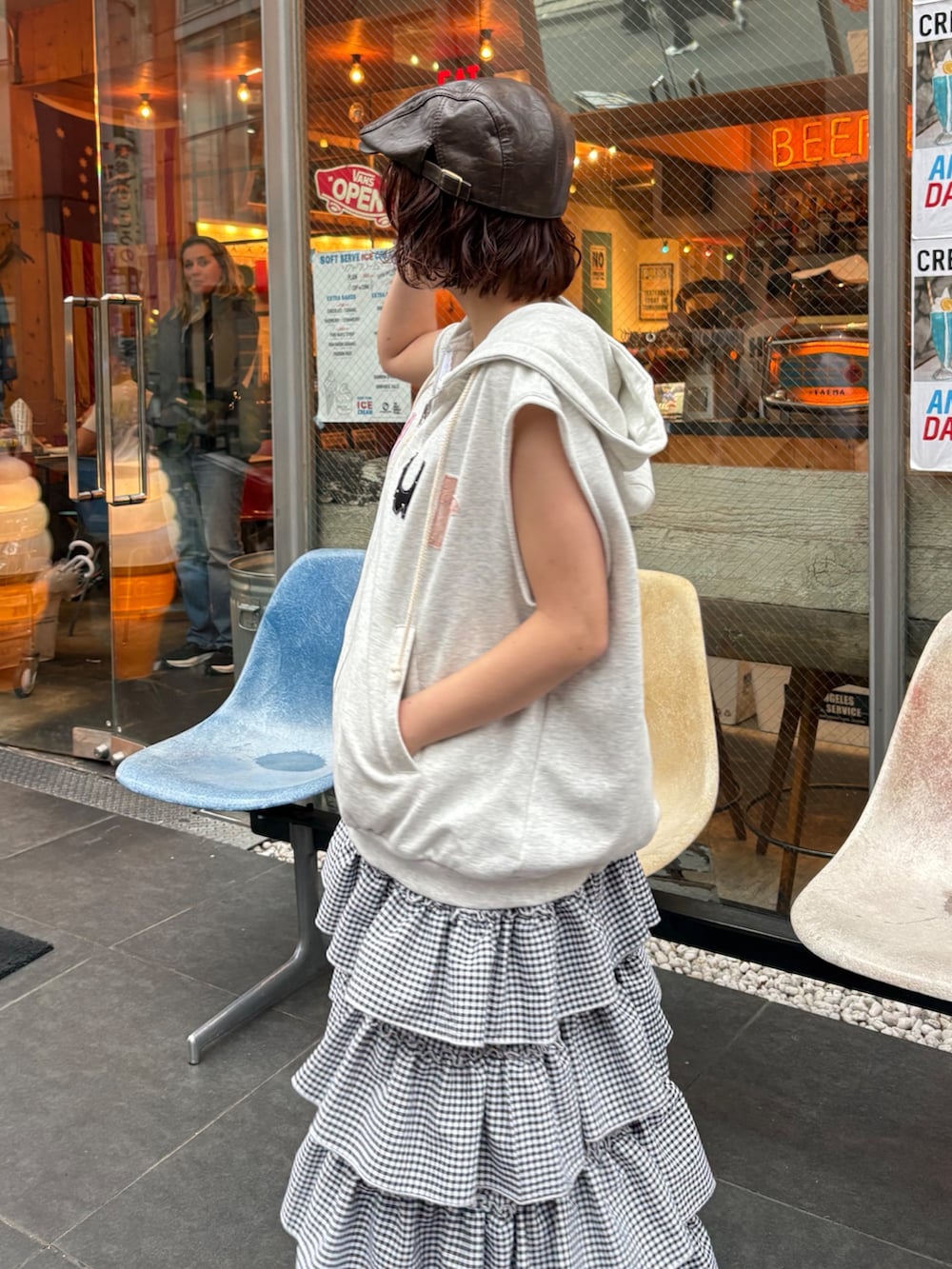 ブラック系のジャンパースカート、ベージュ系のブーツ、ブラウン系のキャップを着用したレディースの春コーディネートの2枚目の写真