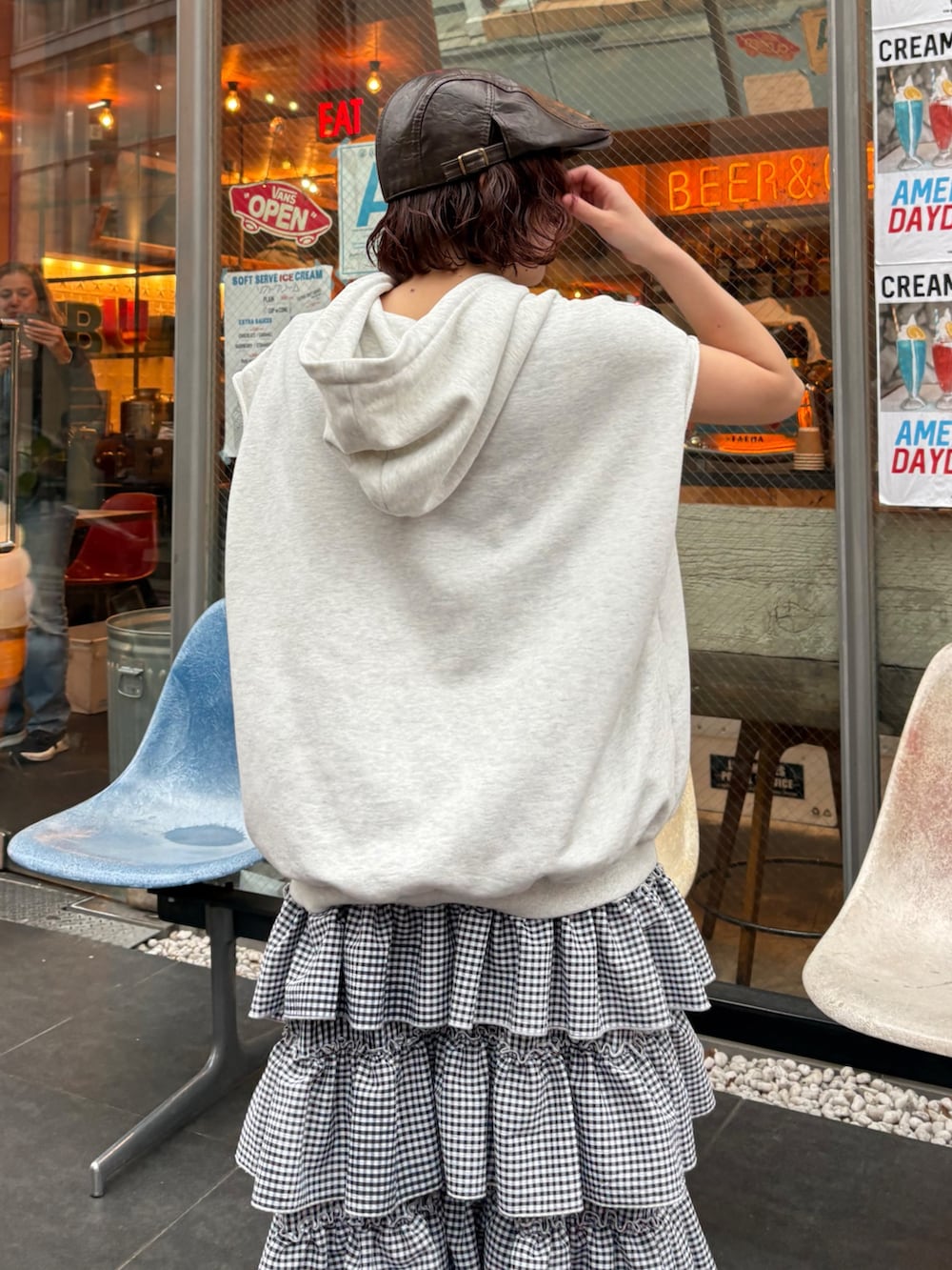 ブラック系のジャンパースカート、ベージュ系のブーツ、ブラウン系のキャップを着用したレディースの春コーディネートの3枚目の写真