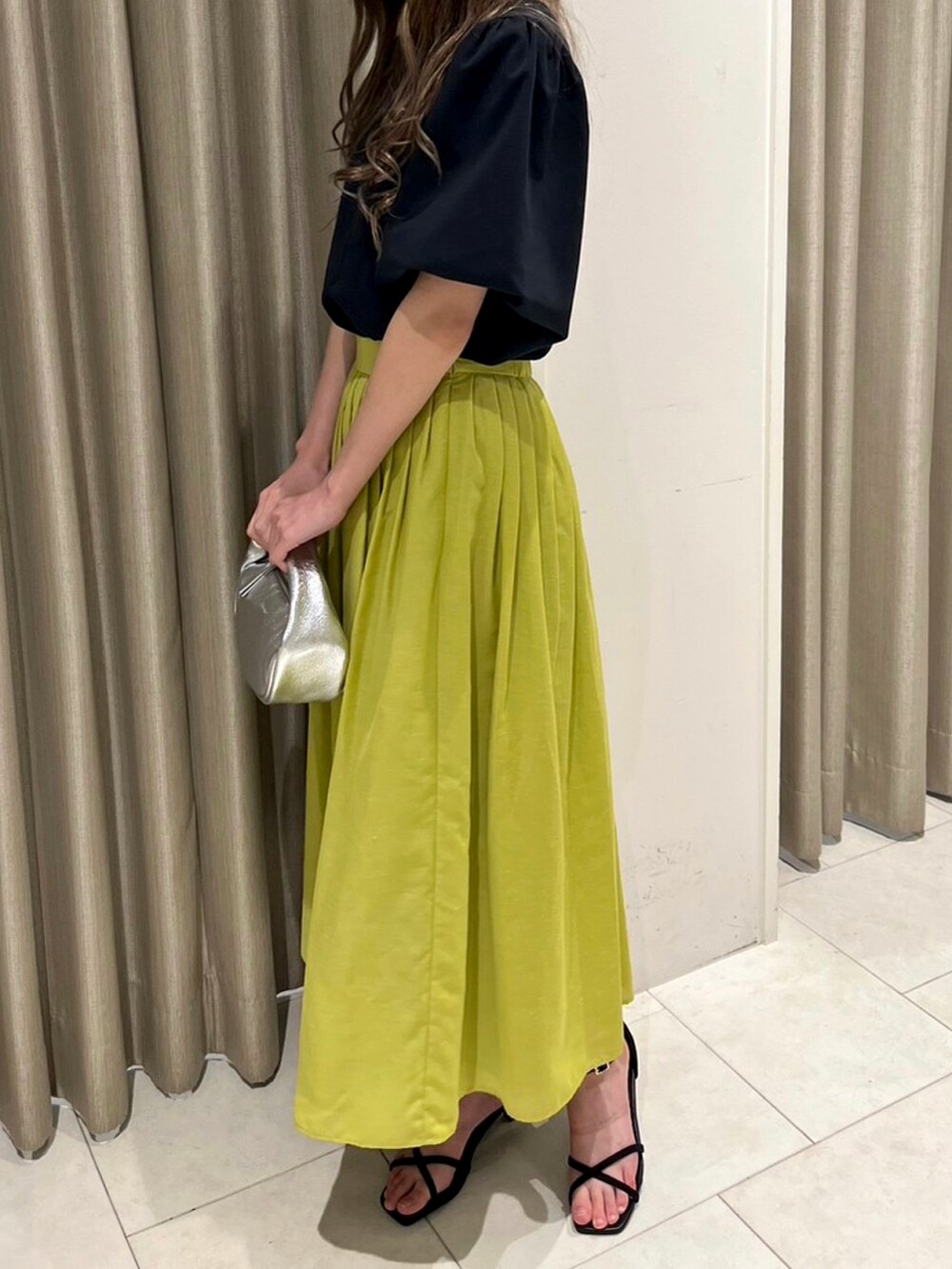 ブラック系のTシャツ/カットソー、イエロー系のスカート、シルバー系のハンドバッグを着用したレディースの春コーディネートの2枚目の写真