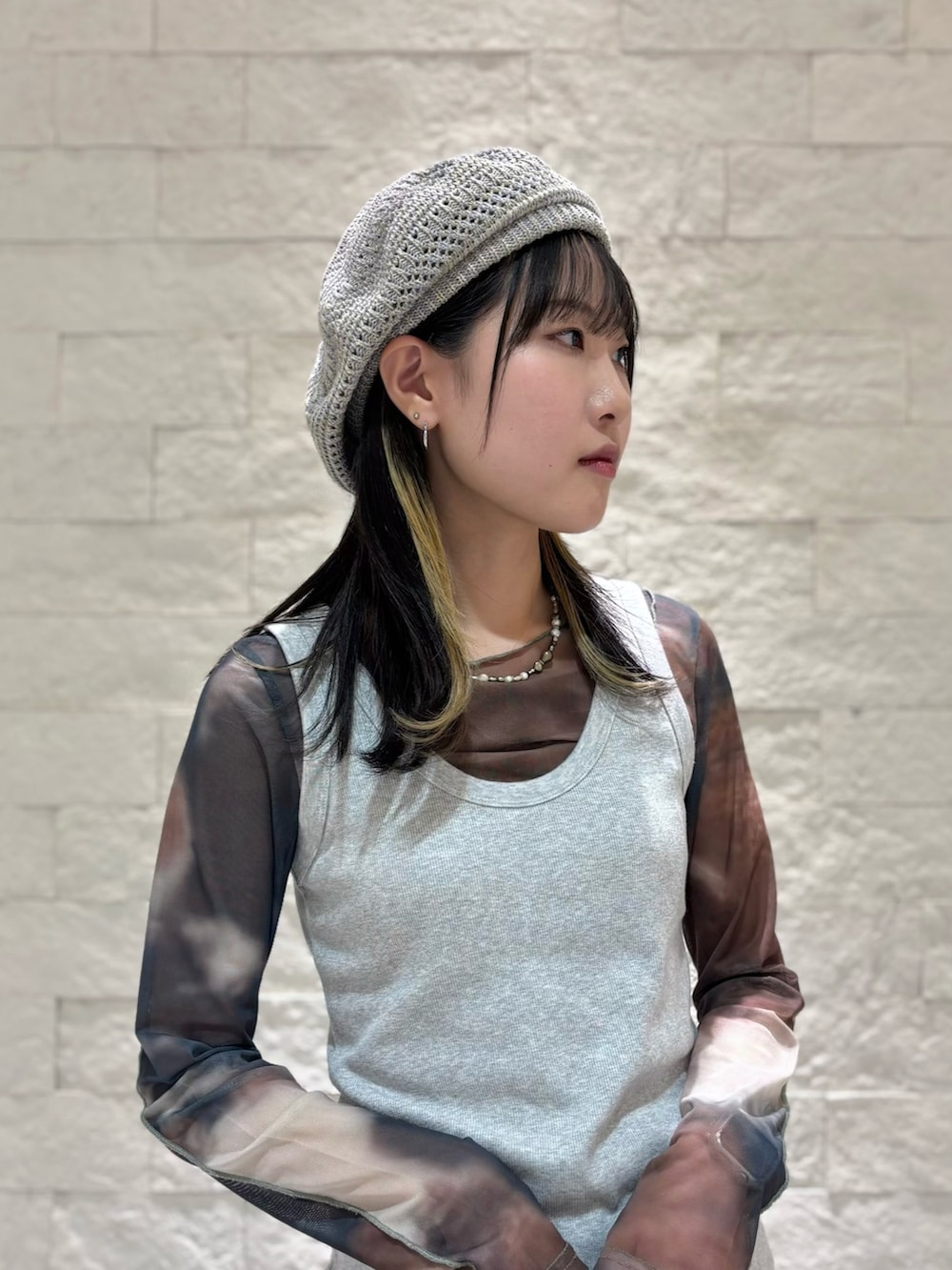 グレー系のタンクトップ、グレー系のスカート、ブラック系のスニーカーを着用したレディースの秋コーディネートの3枚目の写真