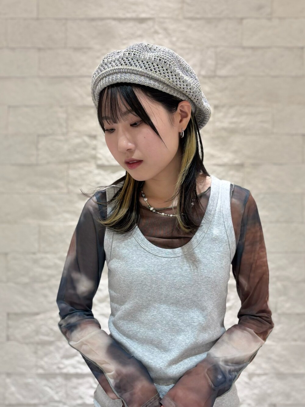 グレー系のタンクトップ、グレー系のスカート、ブラック系のスニーカーを着用したレディースの秋コーディネートの2枚目の写真