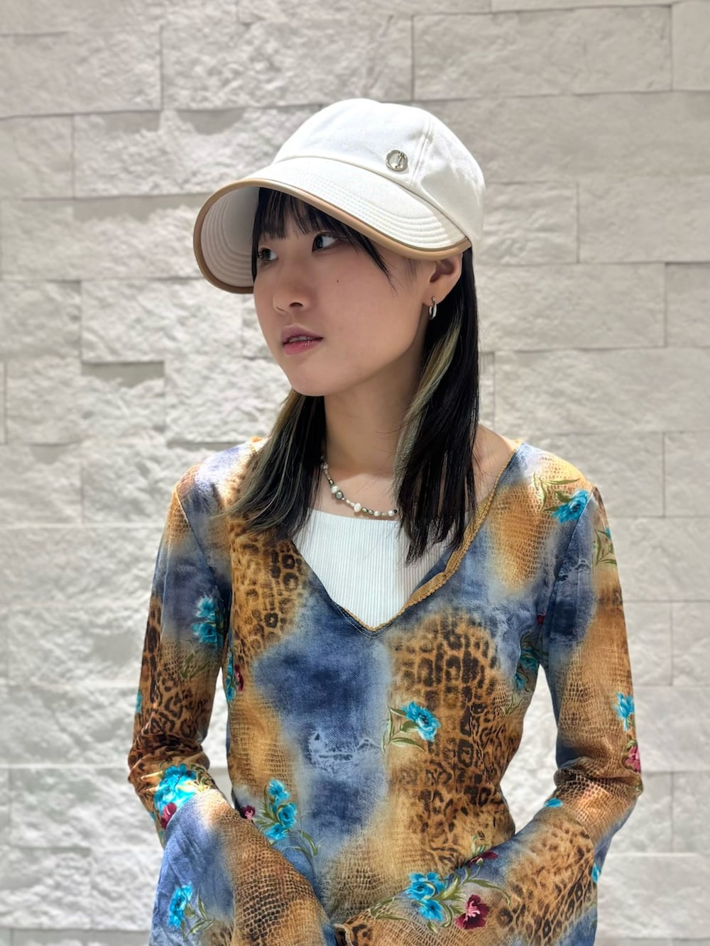 ブルー系のデニムパンツ、ベージュ系のスニーカー、ベージュ系のキャップを着用したレディースの夏コーディネートの4枚目の写真