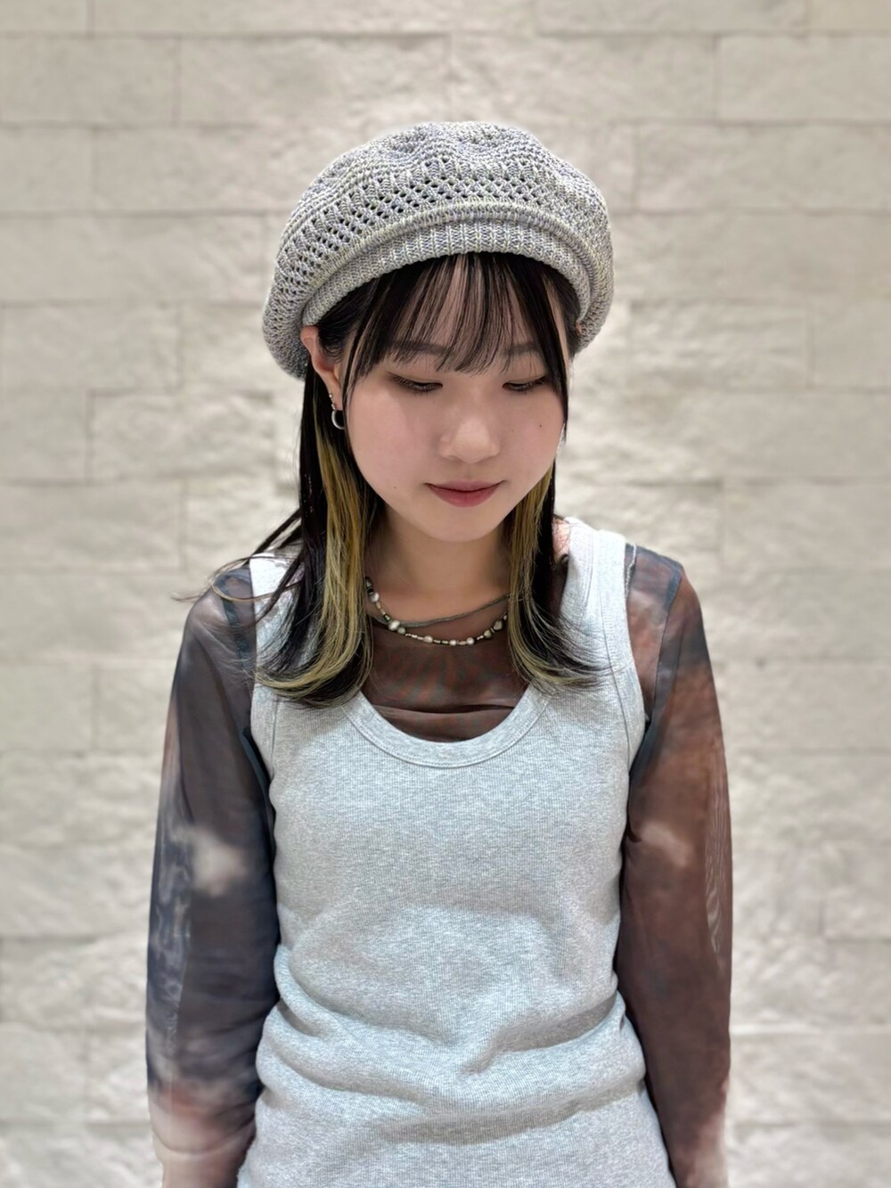 グレー系のタンクトップ、グレー系のスカート、ブラック系のスニーカーを着用したレディースの秋コーディネートの4枚目の写真