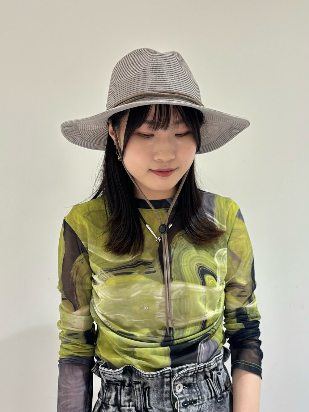 ブラック系のデニムパンツ、ブラック系のシューズ、グレー系のハットを着用したレディースの夏コーディネートの5枚目の写真