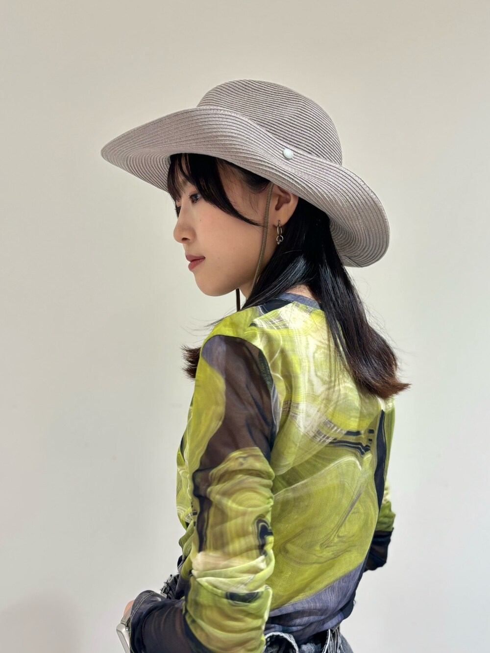 ブラック系のデニムパンツ、ブラック系のシューズ、グレー系のハットを着用したレディースの夏コーディネートの4枚目の写真