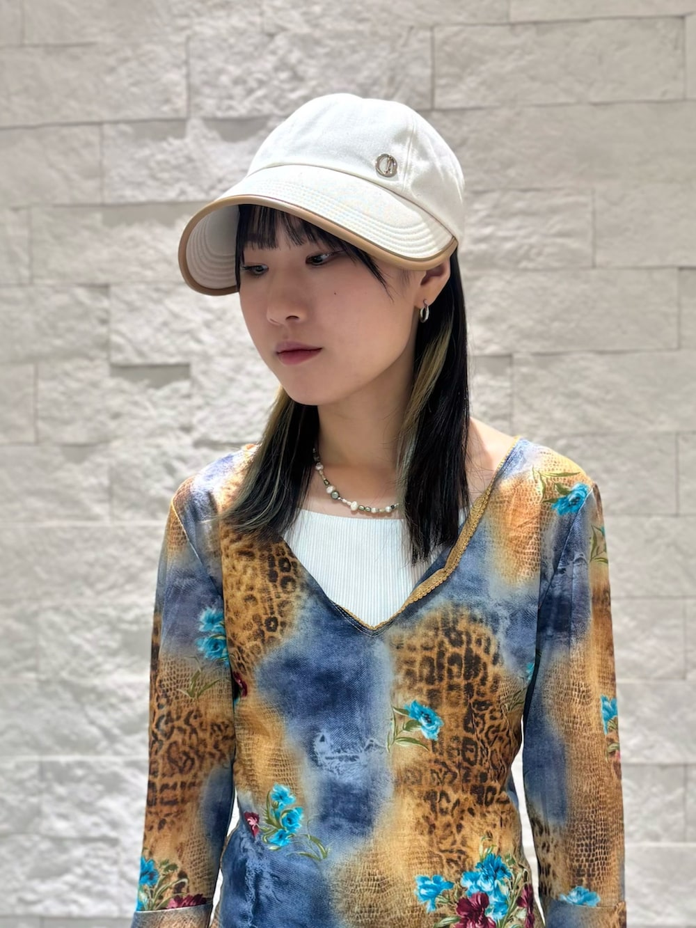 ブルー系のデニムパンツ、ベージュ系のスニーカー、ベージュ系のキャップを着用したレディースの夏コーディネートの2枚目の写真