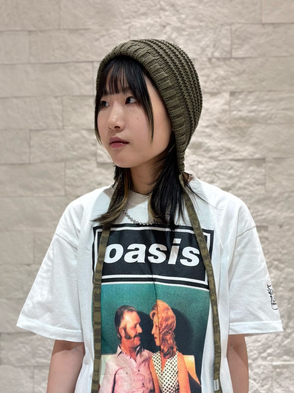 グレー系のスカート、シルバー系のスニーカー、グリーン系のニットキャップ/ビーニーを着用したレディースの夏コーディネートの2枚目の写真