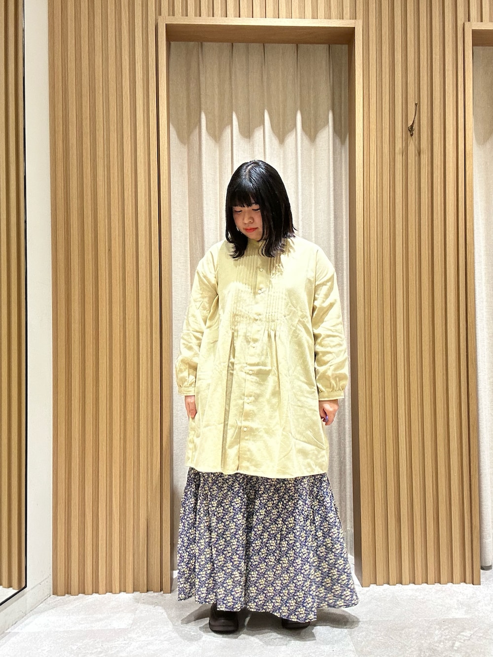 イエロー系のシャツ/ブラウス、ホワイト系のカーディガン/ボレロ、ブルー系のスカートを着用したレディースの冬コーディネートの4枚目の写真