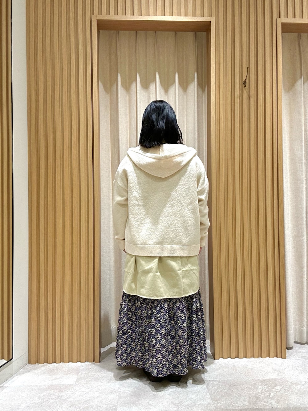 イエロー系のシャツ/ブラウス、ホワイト系のカーディガン/ボレロ、ブルー系のスカートを着用したレディースの冬コーディネートの3枚目の写真