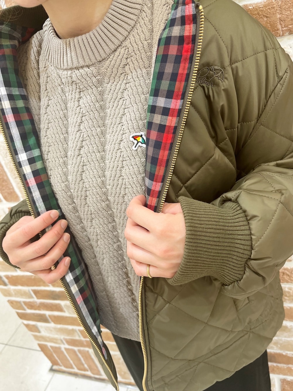 グリーン系のミリタリージャケット、ベージュ系のニット/セーター、ブラック系のスカートを着用したレディースの秋コーディネートの3枚目の写真