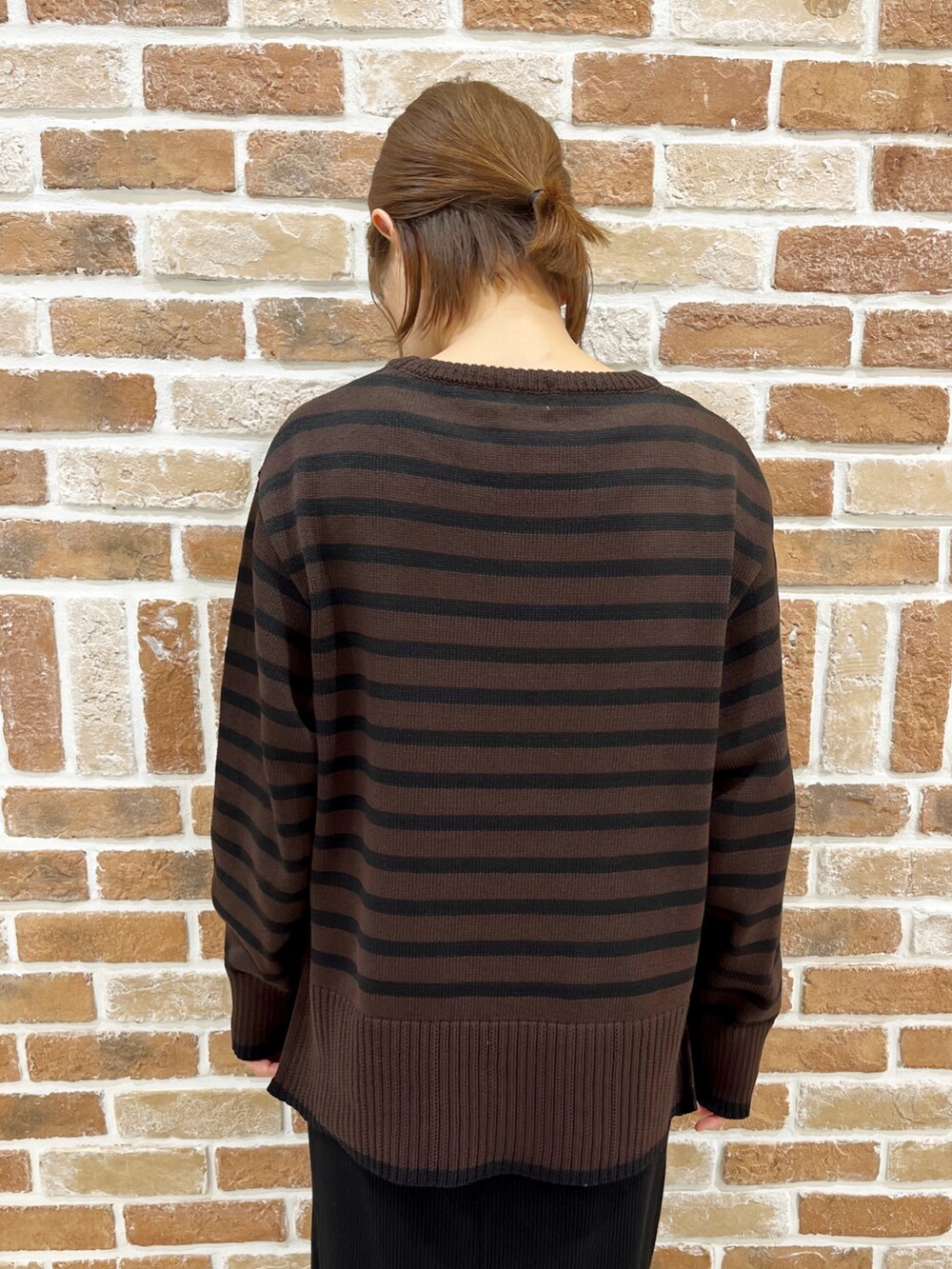 ブラック系のダウンベスト、ブラウン系のニット/セーター、ブラック系のスカートを着用したレディースの秋コーディネートの5枚目の写真