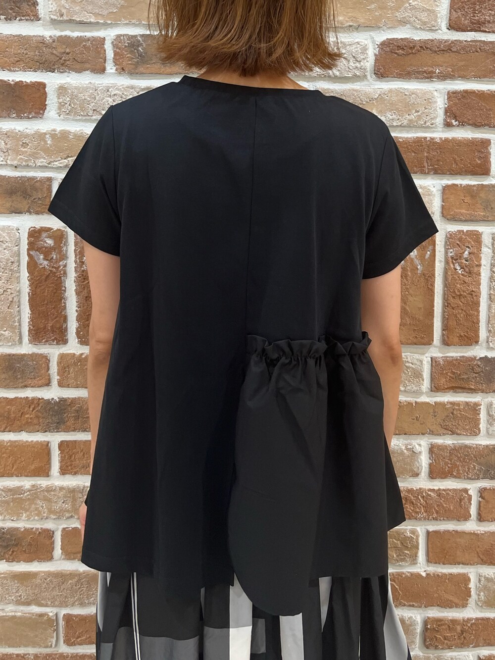 ブラック系のTシャツ/カットソー、ブラック系のスカート、ホワイト系のトートバッグを着用したレディースの夏コーディネートの5枚目の写真