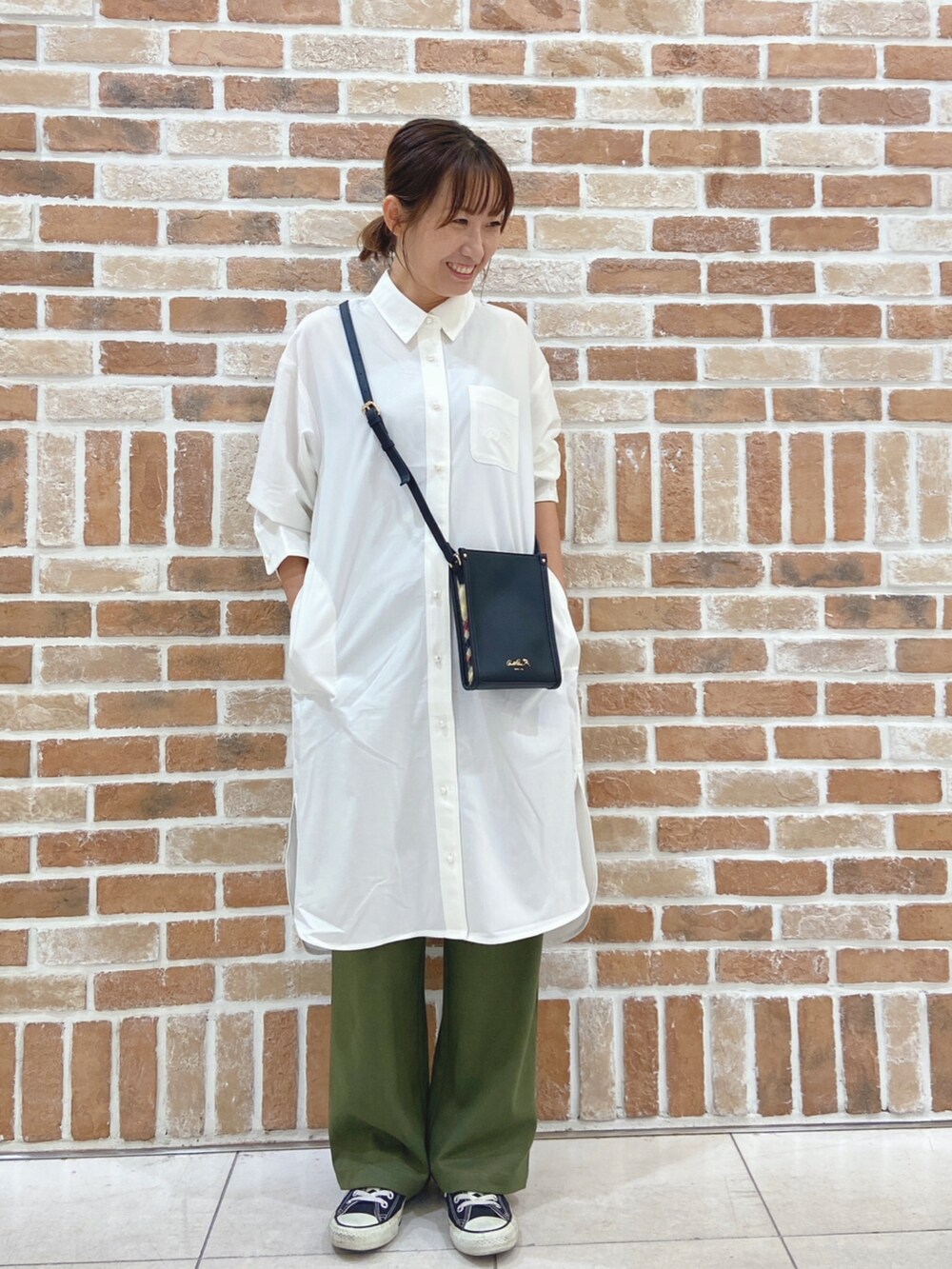 ブラック系のショルダーバッグ、ホワイト系のワンピース、グリーン系のチノパンツを着用したレディースの秋コーディネートの2枚目の写真