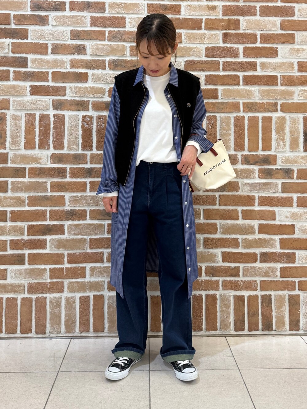 ブルー系のシャツワンピース、ブラック系のベスト、レッド系のショルダーバッグを着用したレディースの秋コーディネートの2枚目の写真