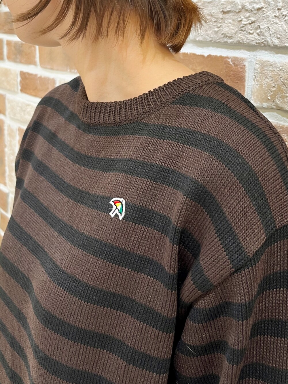 ブラック系のダウンベスト、ブラウン系のニット/セーター、ブラック系のスカートを着用したレディースの秋コーディネートの6枚目の写真