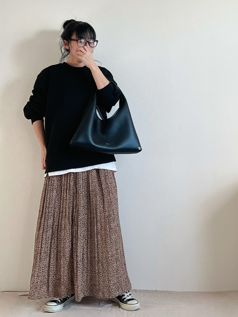 ブラック系のバッグ、ブラウン系のスカート、ブラック系のスニーカーを着用したレディースの冬コーディネートの2枚目の写真