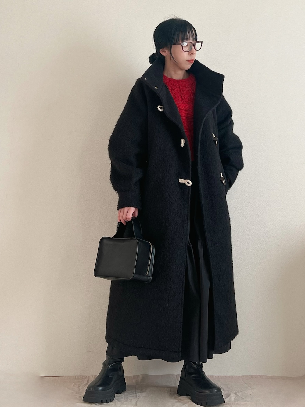 レッド系のニット/セーター、ブラック系のスカート、ブラック系のブーツを着用したレディースの冬コーディネートの4枚目の写真