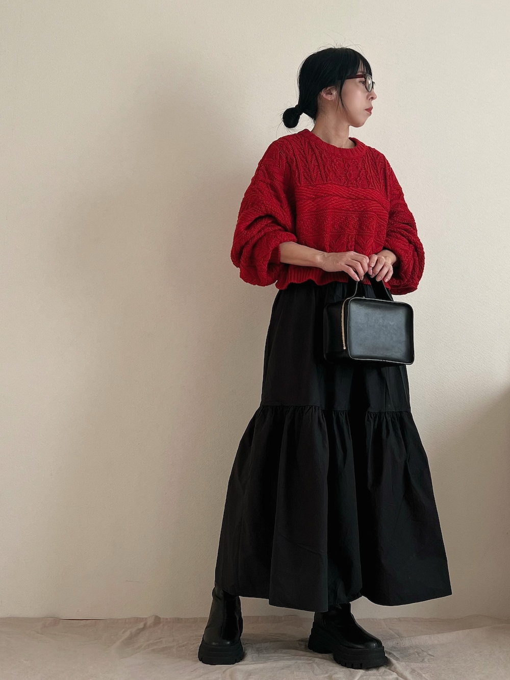 レッド系のニット/セーター、ブラック系のスカート、ブラック系のブーツを着用したレディースの冬コーディネートの3枚目の写真