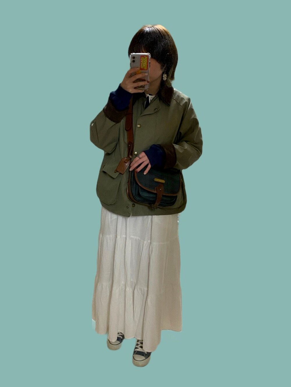 ホワイト系のスカート、ブルー系のスニーカー、グリーン系のその他アウターを着用したレディースの春コーディネートの2枚目の写真