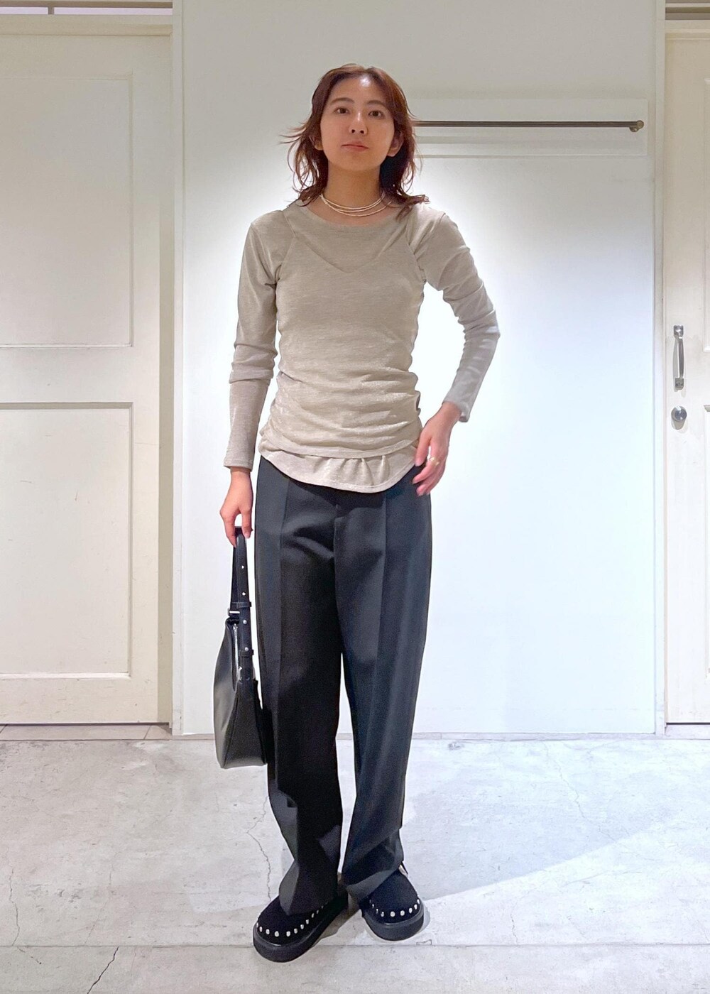 ブラック系のショルダーバッグ、グレー系のスラックス、ゴールド系のTシャツ/カットソーを着用したレディースの秋コーディネートの2枚目の写真