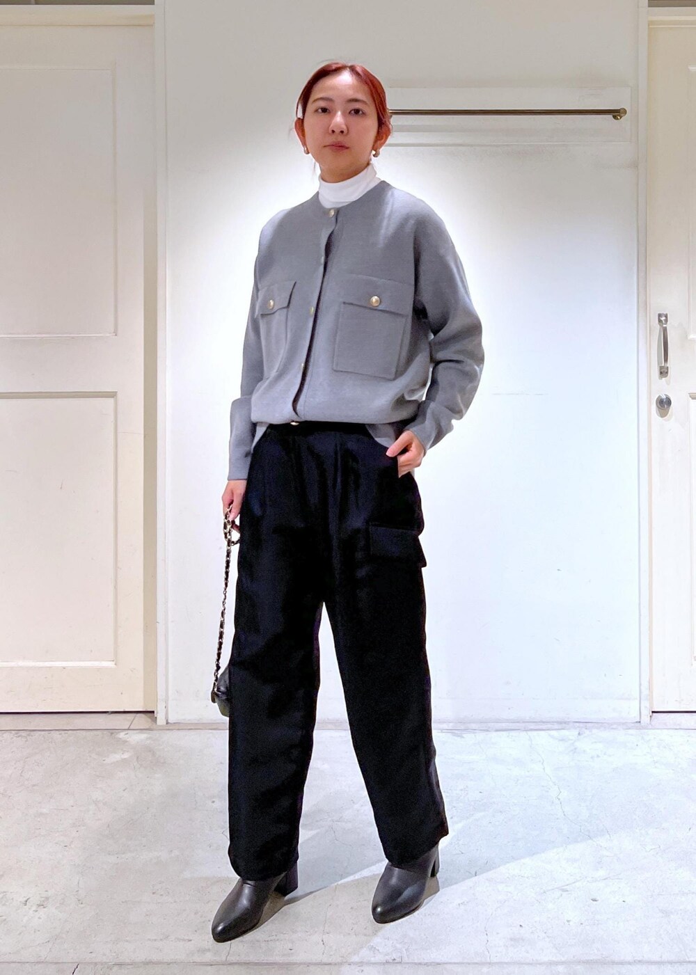 ブラック系のショルダーバッグ、ブラック系のブーツ、ホワイト系のTシャツ/カットソーを着用したレディースの冬コーディネートの2枚目の写真