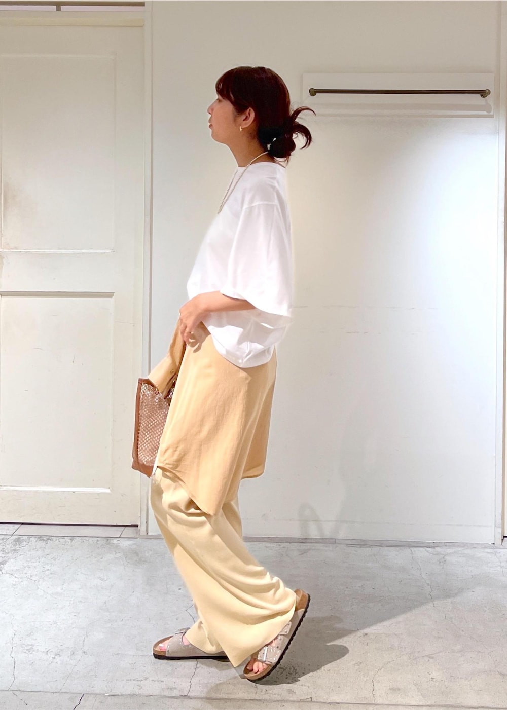 イエロー系のトートバッグ、ホワイト系のシャツ/ブラウス、ホワイト系のその他パンツを着用したレディースの夏コーディネートの3枚目の写真
