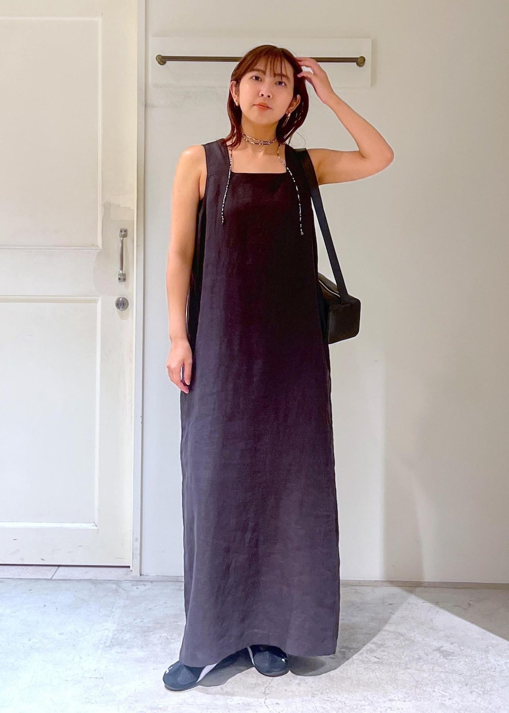 ブラック系のショルダーバッグ、ブラック系のジャンパースカート、ブラック系のスニーカーを着用したレディースの夏コーディネートの3枚目の写真