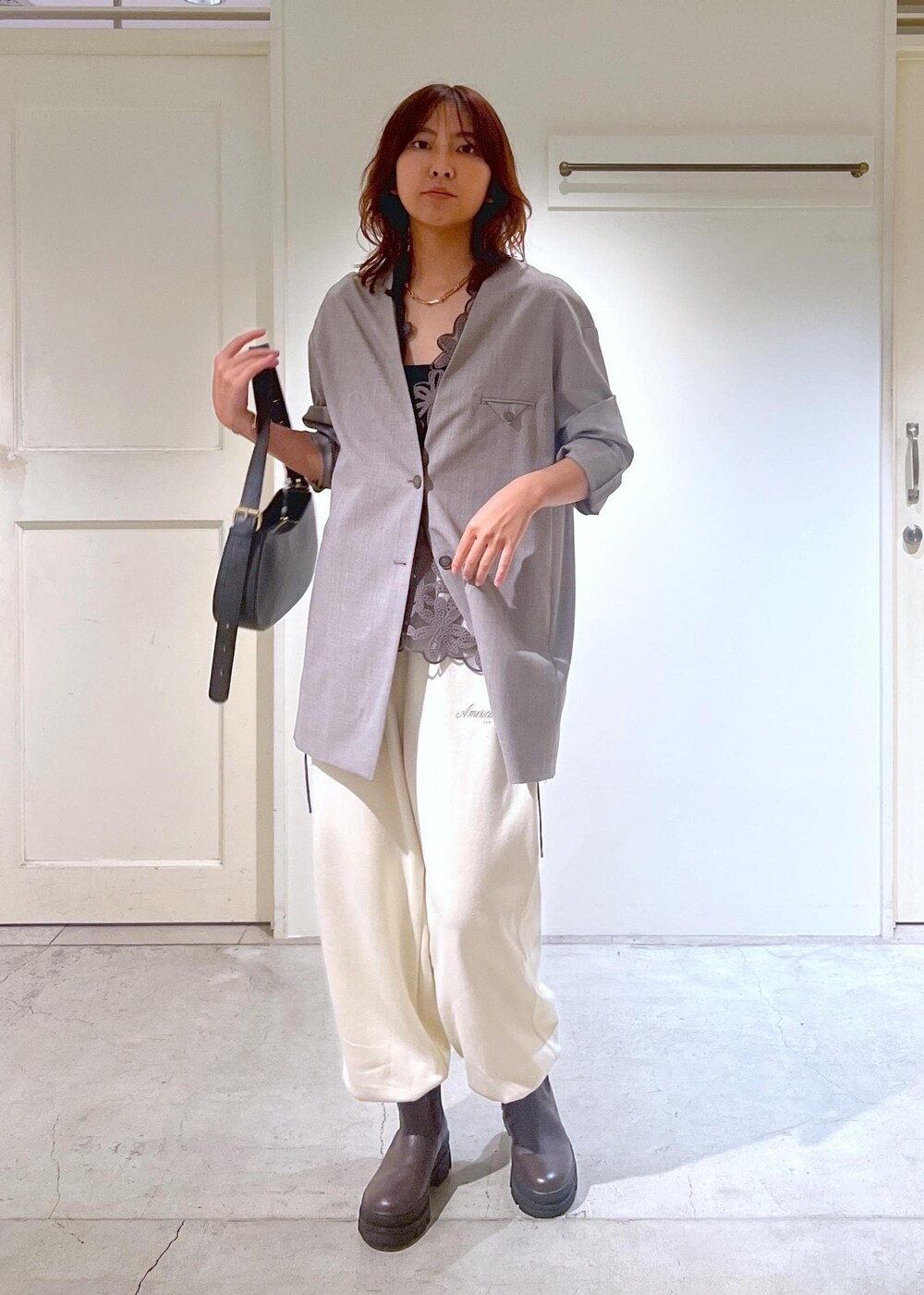 グレー系のノーカラージャケット、ホワイト系のスウェットパンツ、ブラック系のショルダーバッグを着用したレディースの秋コーディネートの2枚目の写真