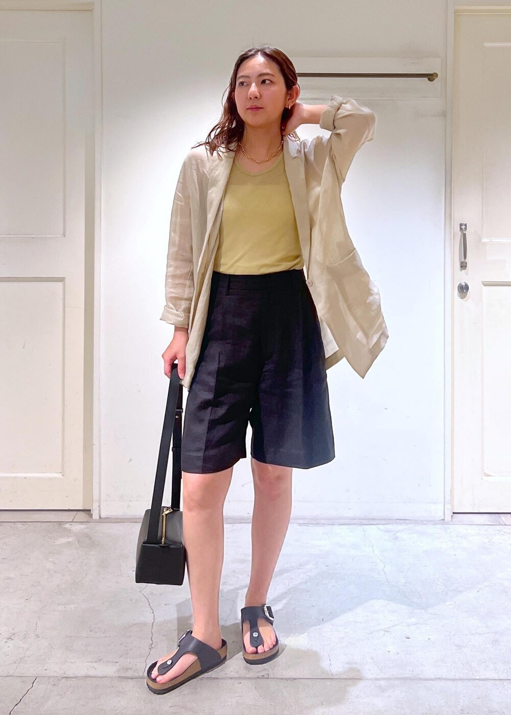 ブラック系のショルダーバッグ、ベージュ系のテーラードジャケット、ブラック系のその他パンツを着用したレディースの夏コーディネートの4枚目の写真