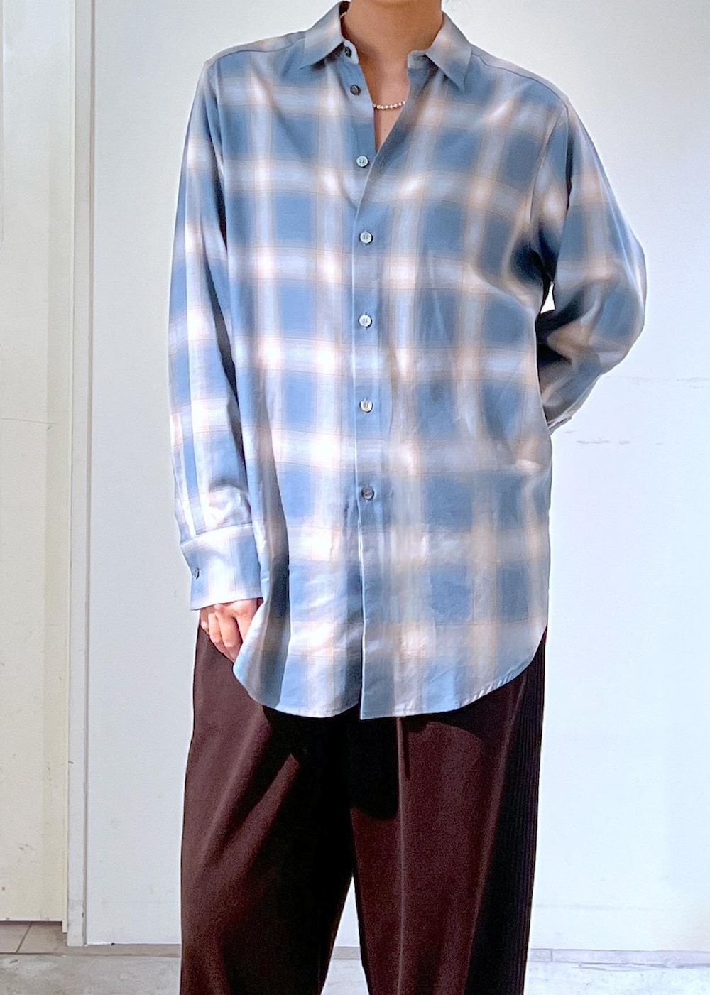 ブルー系のシャツ/ブラウス、ブラウン系のハンドバッグ、シルバー系のネックレスを着用したレディースの秋コーディネートの4枚目の写真