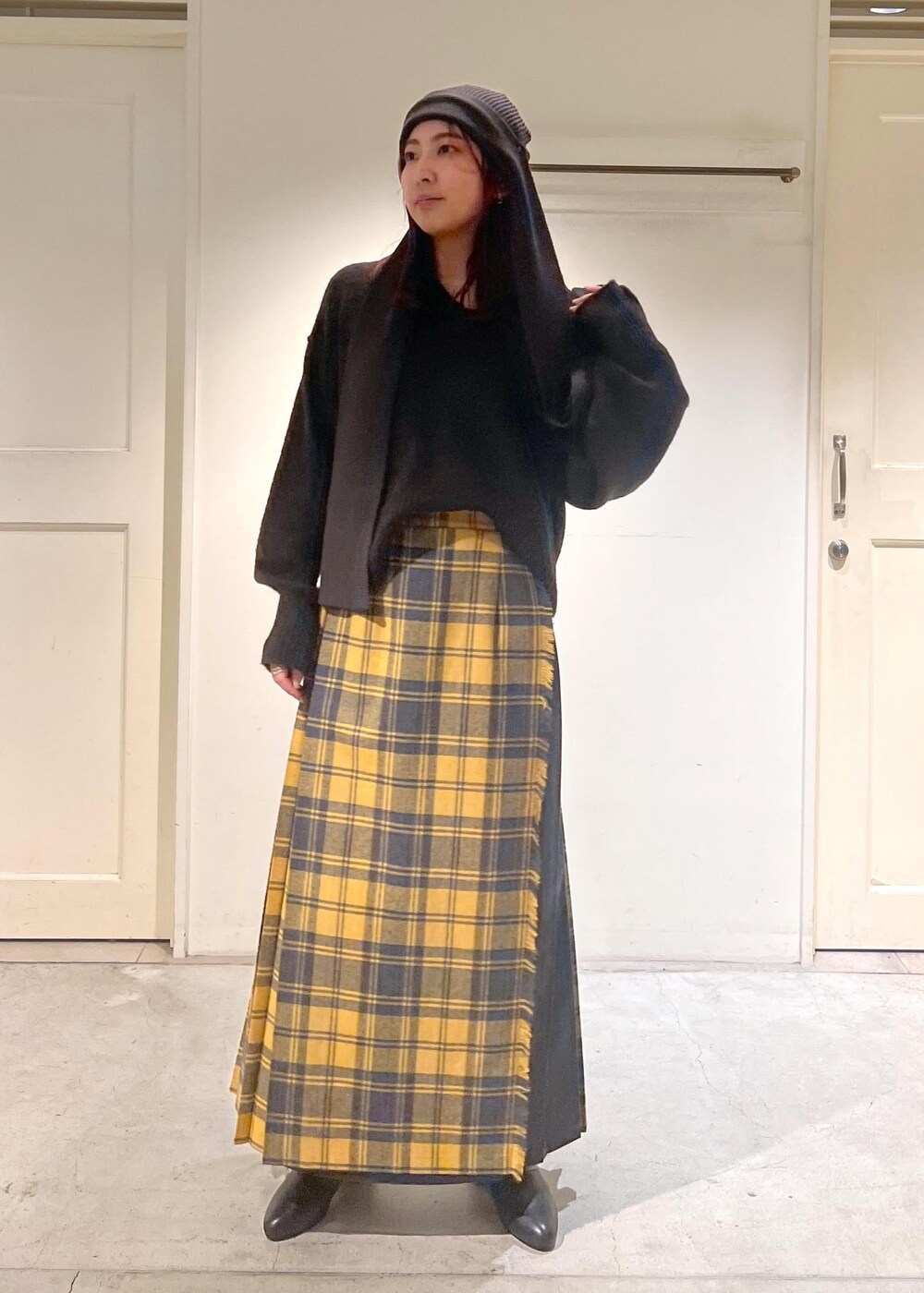 イエロー系のスカート、ブラック系のブーツ、ブラウン系のニット/セーターを着用したレディースの秋コーディネートの5枚目の写真