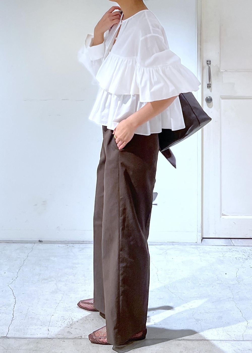 ブラウン系のスラックス、ブラウン系のローファー、ホワイト系のシャツ/ブラウスを着用したレディースの冬コーディネートの4枚目の写真