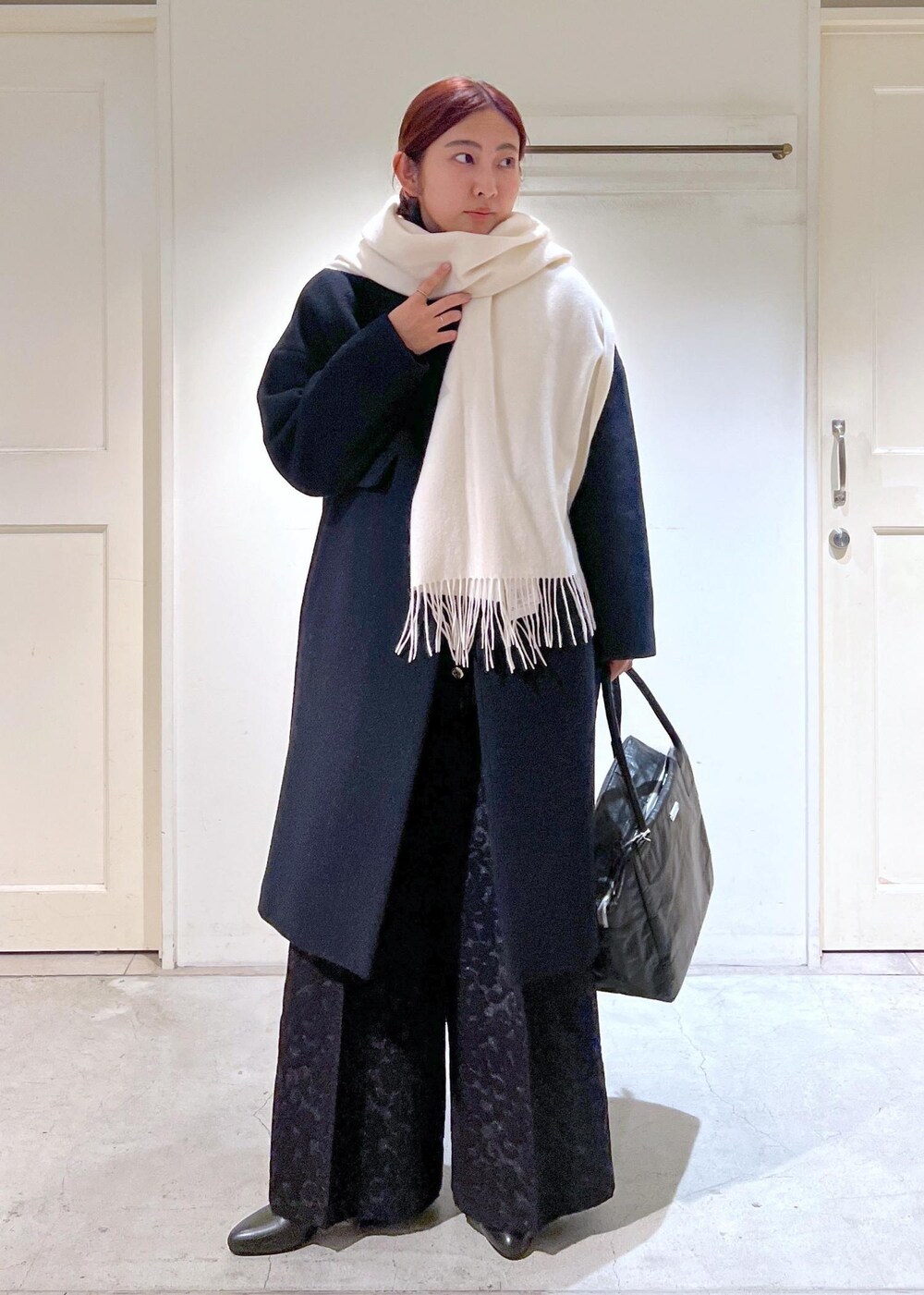 ブラック系のチェスターコート、ブラック系のブーツ、ブラック系のその他パンツを着用したレディースの冬コーディネートの2枚目の写真