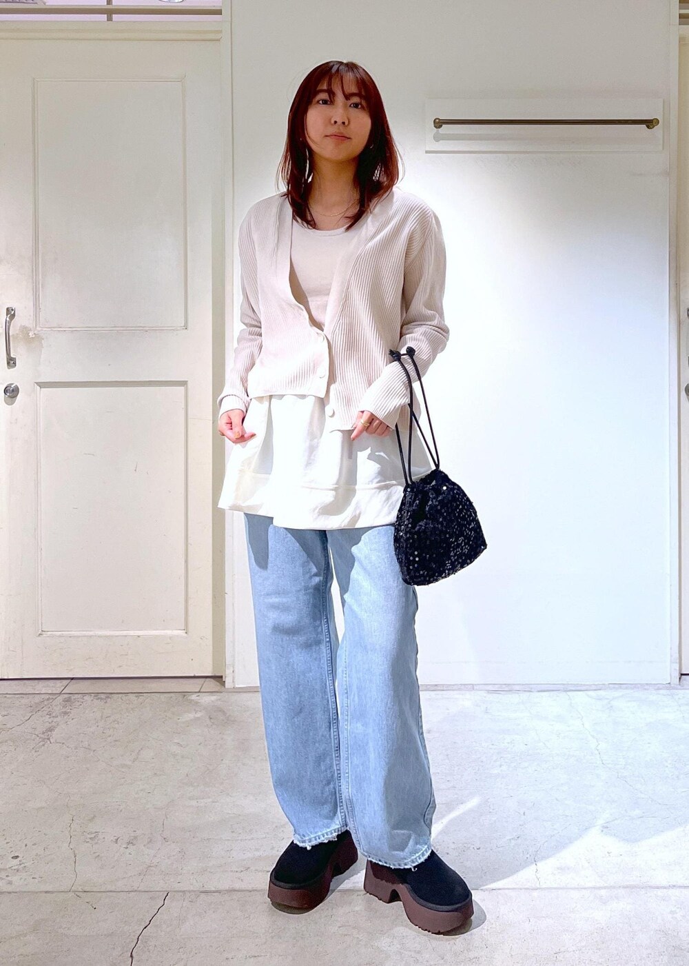 ブラック系のブーツ、ホワイト系のタンクトップ、ブラック系のハンドバッグを着用したレディースの冬コーディネートの2枚目の写真