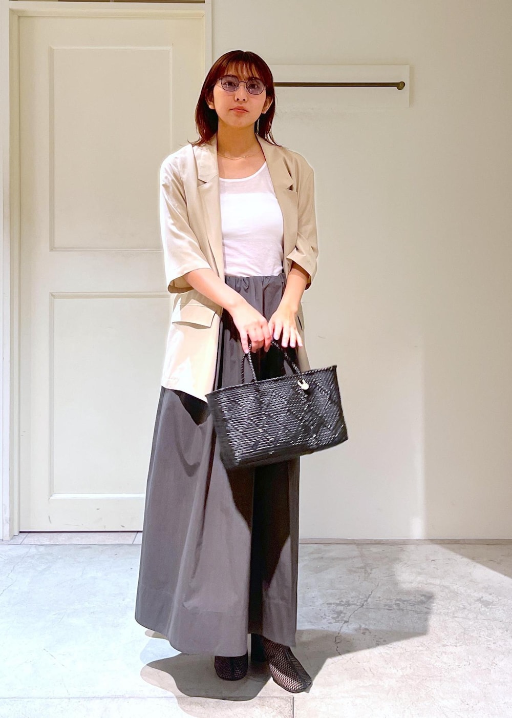 ブラック系のかごバッグ、ベージュ系のシャツ/ブラウス、グレー系のスカートを着用したレディースの春コーディネートの2枚目の写真