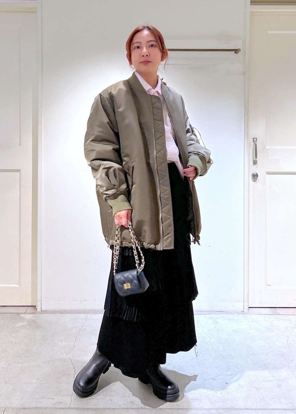 ブラック系のショルダーバッグ、グリーン系のMA-1、ブラック系のスカートを着用したレディースの冬コーディネートの3枚目の写真