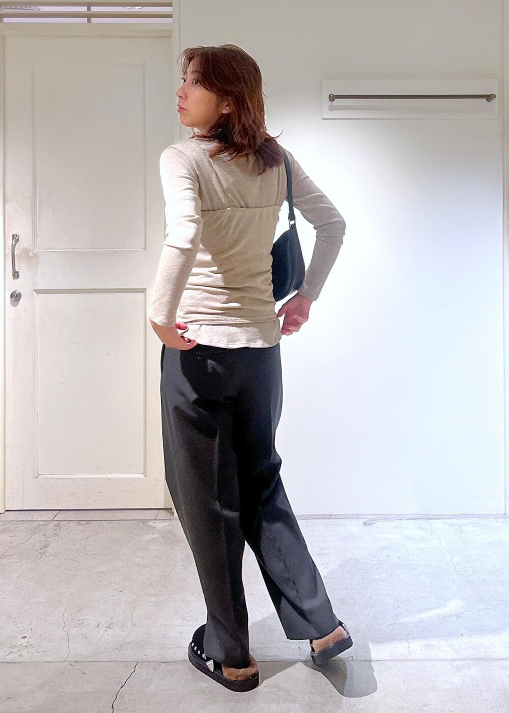 ブラック系のショルダーバッグ、グレー系のスラックス、ゴールド系のTシャツ/カットソーを着用したレディースの秋コーディネートの3枚目の写真