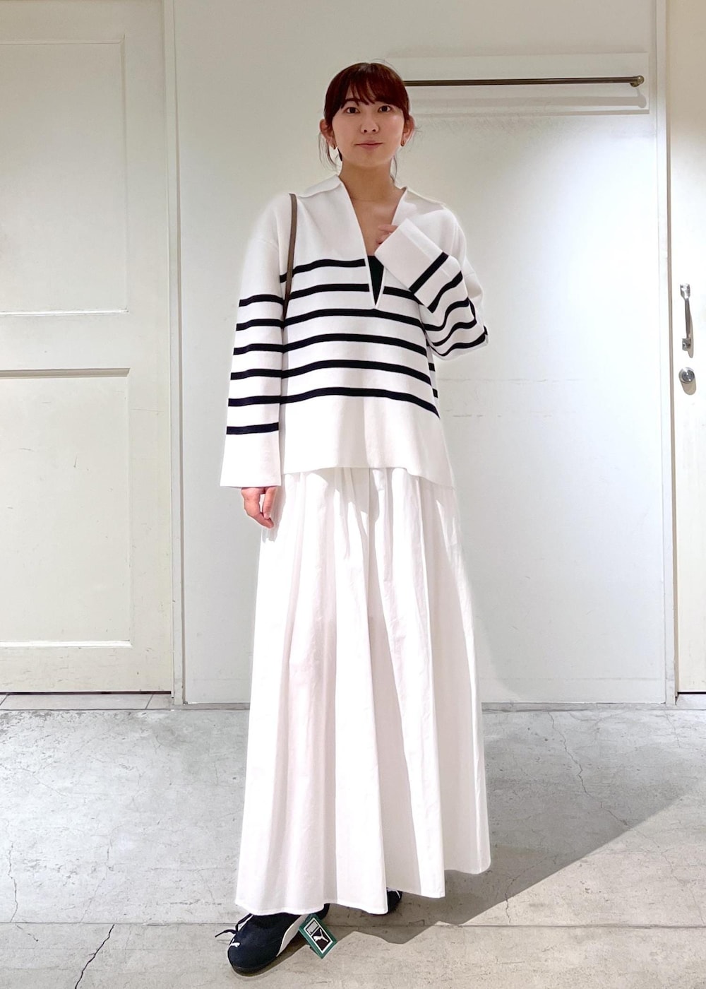 ホワイト系のニット/セーター、ホワイト系のスカート、ベージュ系のショルダーバッグを着用したレディースの春コーディネートの2枚目の写真