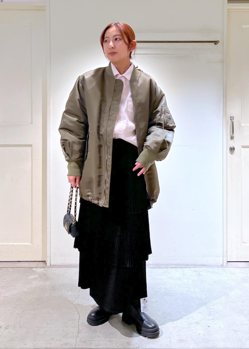 ブラック系のショルダーバッグ、グリーン系のMA-1、ブラック系のスカートを着用したレディースの冬コーディネートの2枚目の写真