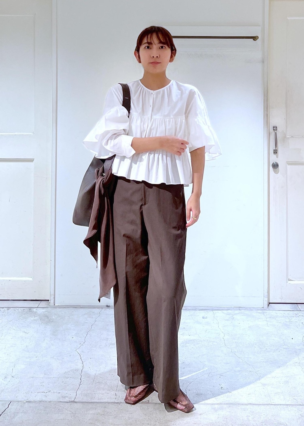 ブラウン系のスラックス、ブラウン系のローファー、ホワイト系のシャツ/ブラウスを着用したレディースの冬コーディネートの2枚目の写真