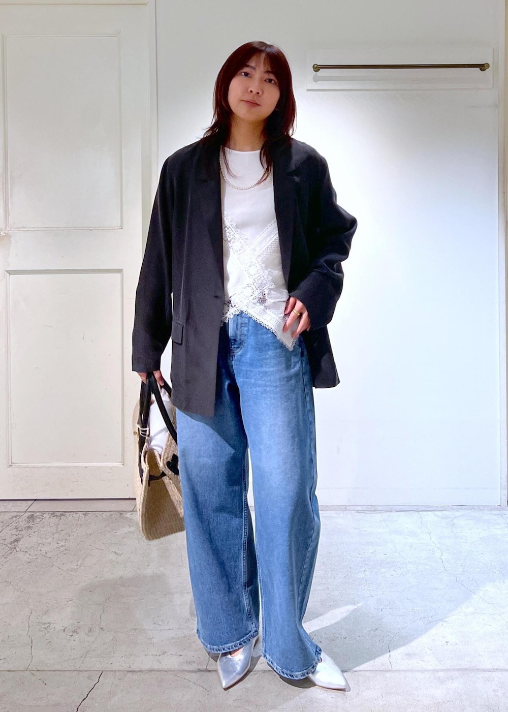 ブルー系のデニムパンツ、ホワイト系のトートバッグ、ホワイト系のキャミソールを着用したレディースの春コーディネートの2枚目の写真