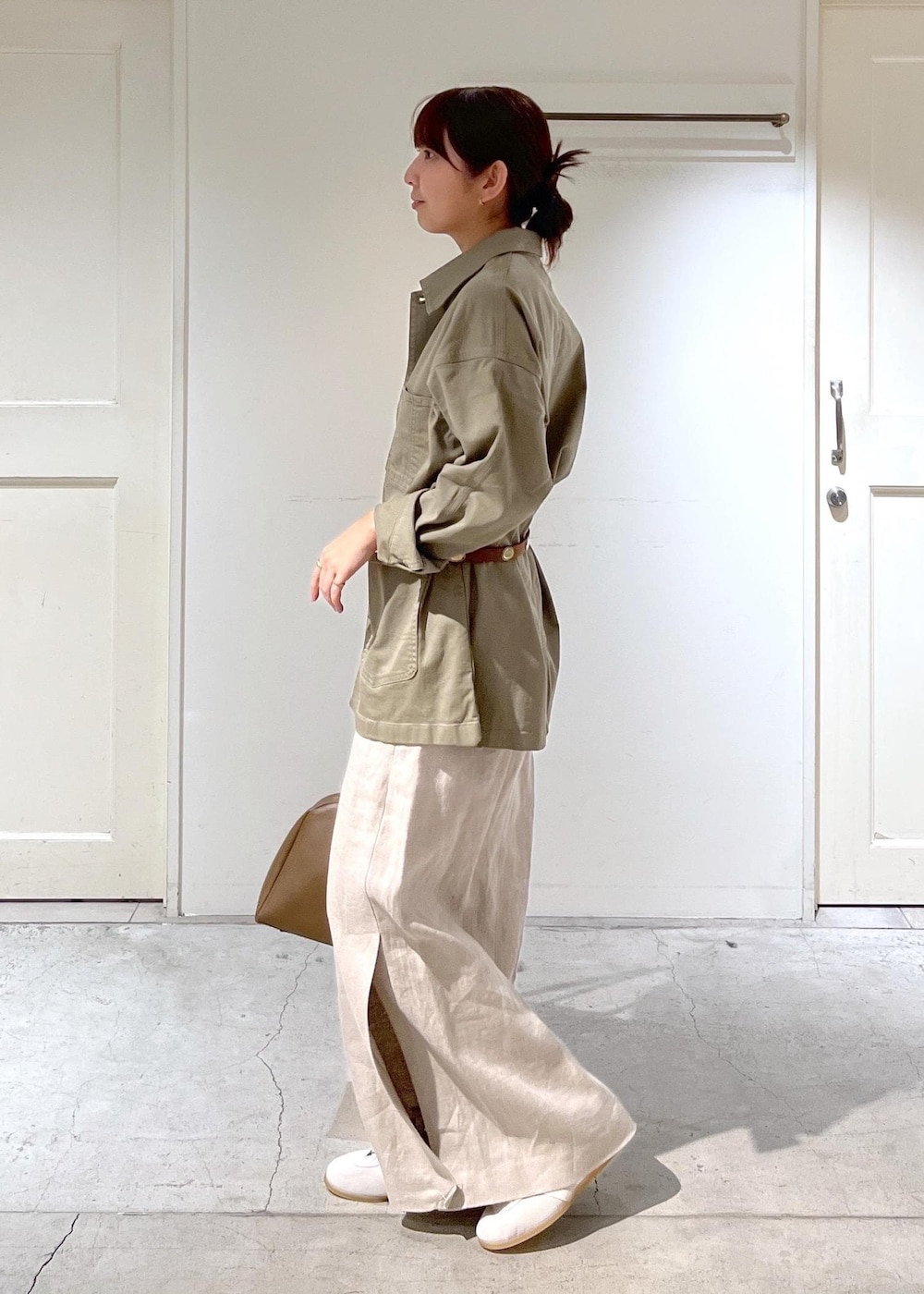 ブラウン系のボストンバッグ、ベージュ系のスカート、グリーン系のカバーオールを着用したレディースの春コーディネートの4枚目の写真